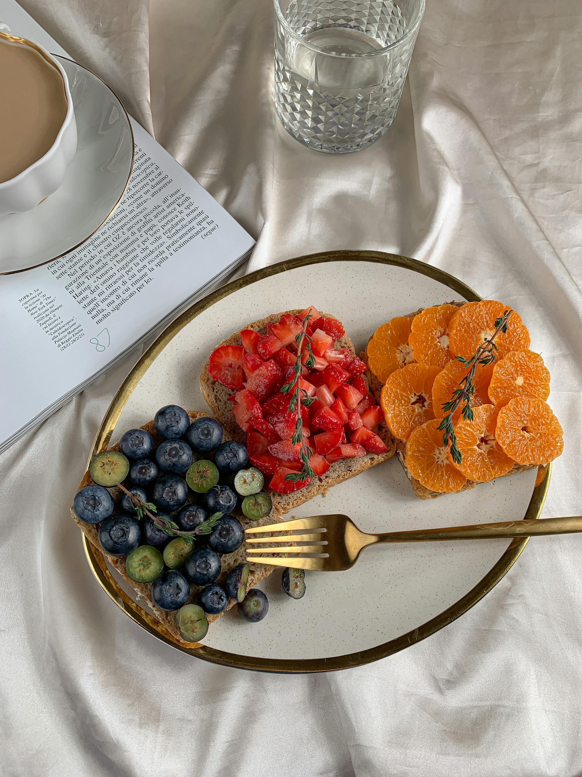 Fresh fruit toasts with blueberries, strawberries, and oranges on a ceramic plate.