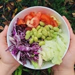 A vibrant bowl of fresh garden salad featuring tomatoes, edamame, and cabbage. Perfect for healthy dining.