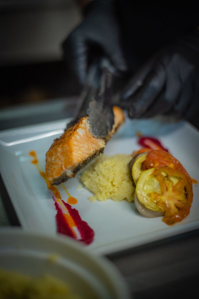 A gourmet salmon dish served with couscous and roasted vegetables artfully plated.