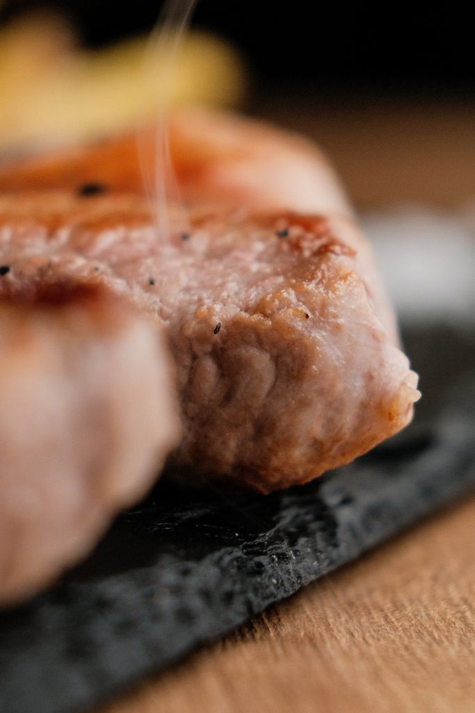 Close-up view of a steaming, juicy grilled steak on a slate surface.