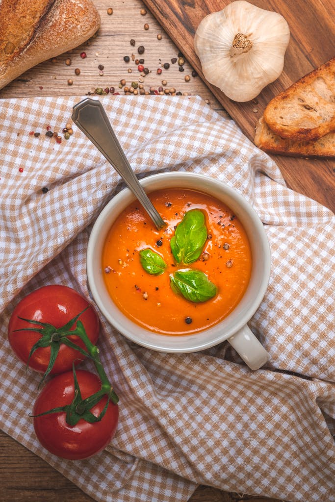 Creamy tomato soup garnished with basil, served with bread and garlic.