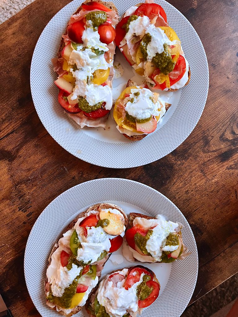 Delicious bruschetta topped with fresh tomatoes, burrata, and pesto on a wooden table.