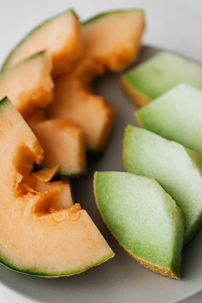 High angle of plate with ripe organic cut cantaloupe and honeydew melons placed on white plate