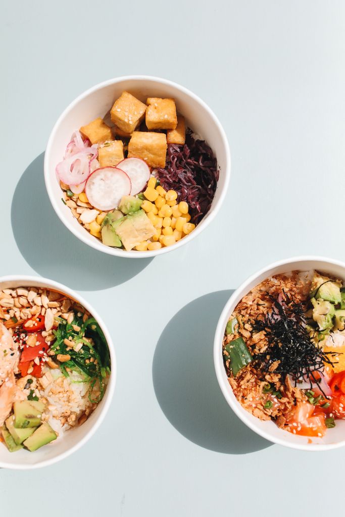Three colorful poke bowls with fresh ingredients like avocado, corn, and tofu.