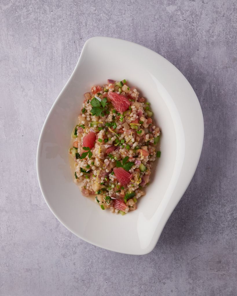 Top-down view of tuna porridge garnished with herbs in a ceramic dish on a gray surface.