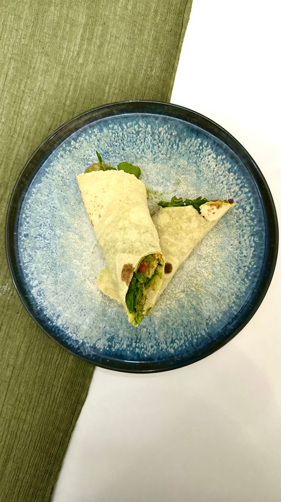 Top view of a fresh vegetable wrap on a blue ceramic plate, perfect for a healthy meal.